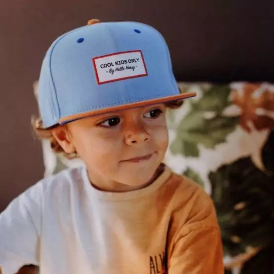 czapka dla dziecka chłopiec siedzący w niebieskiej czapce z daszkiem dostosowanej do jego wieku