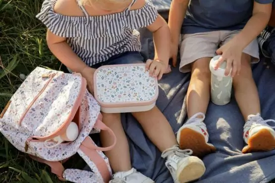 chłopiec oraz dziewczynka siedzą na kocu podczas pikniku z bidonem oraz śniadaniówką akcesoria dla dzieci